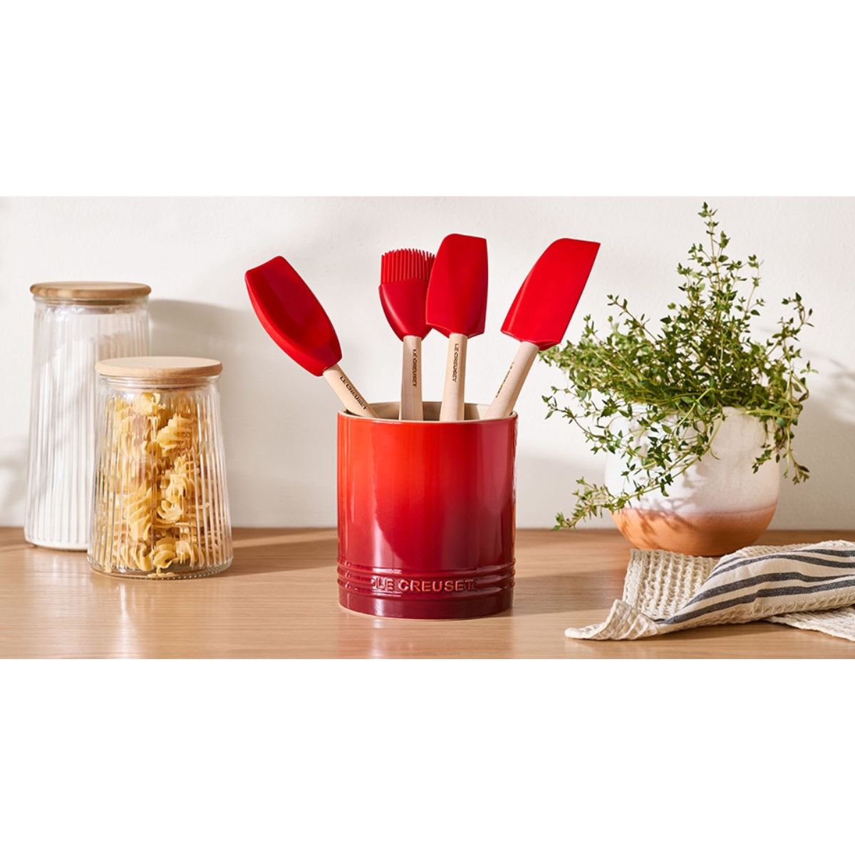 Le Creuset Spatula Set with Crock Cerise (5 Piece) | Minimax - on a table with plant