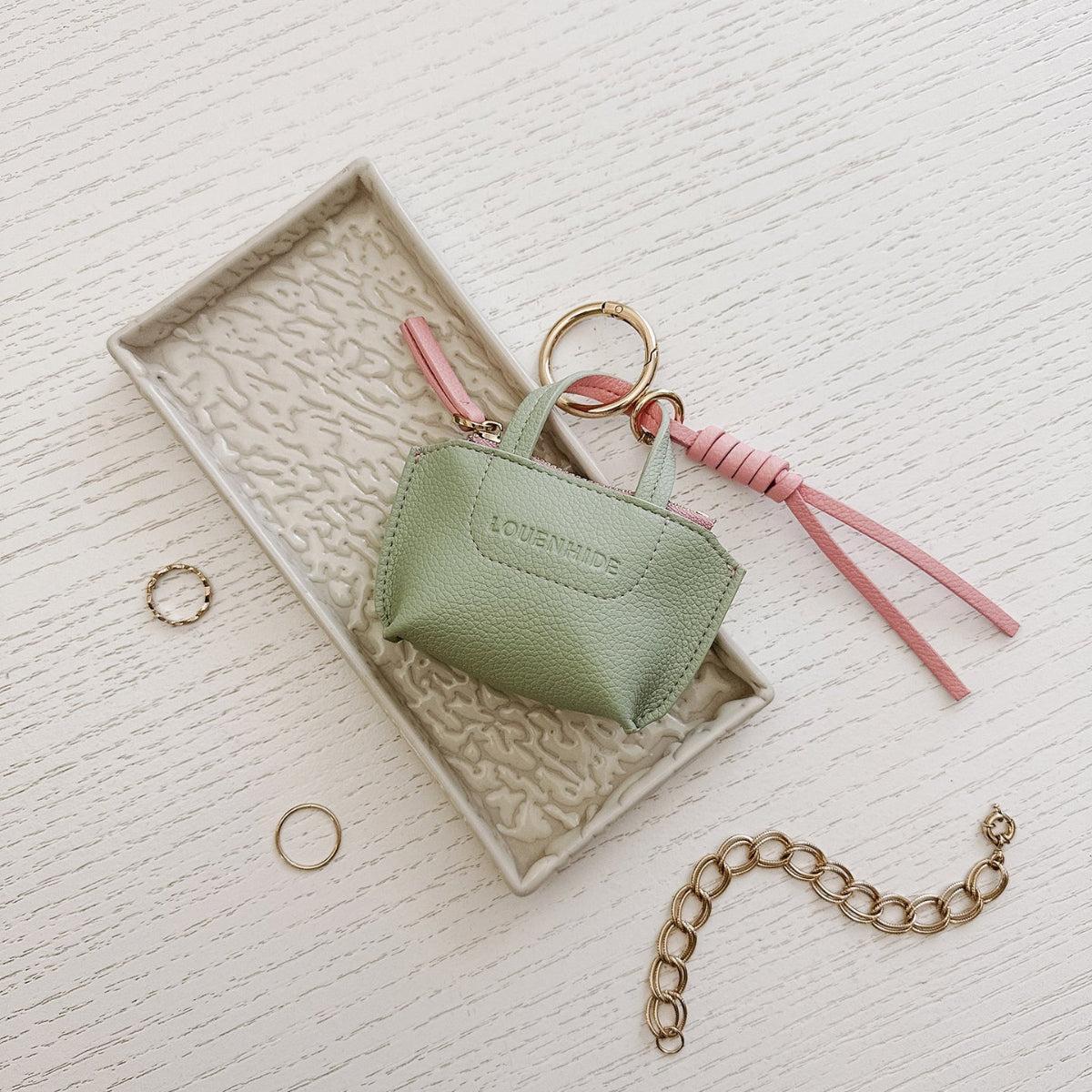 Louenhide Gina Bag Charm Sage Green shaped like a mini handbag with pink strap detail