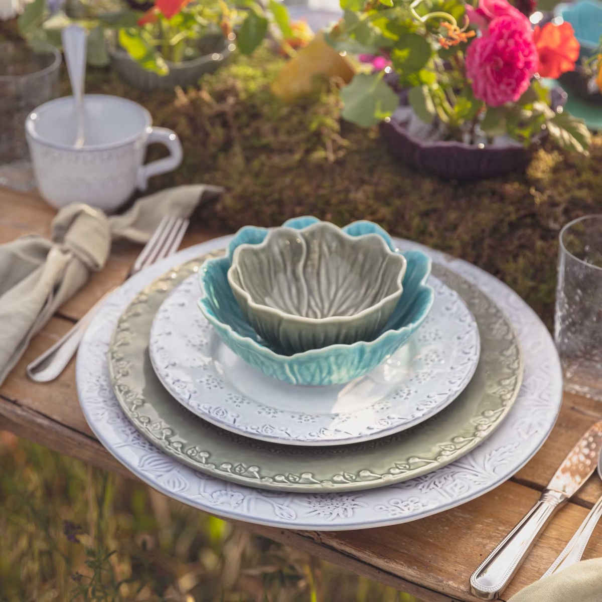 Bordallo Pinheiro Flora Bowl Blue 17cm – Close-up of blue floral bowl stacked on plates in outdoor table setting