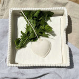 Ceramic Heart Napkin Holder White displayed with blue patterned napkins on wooden table