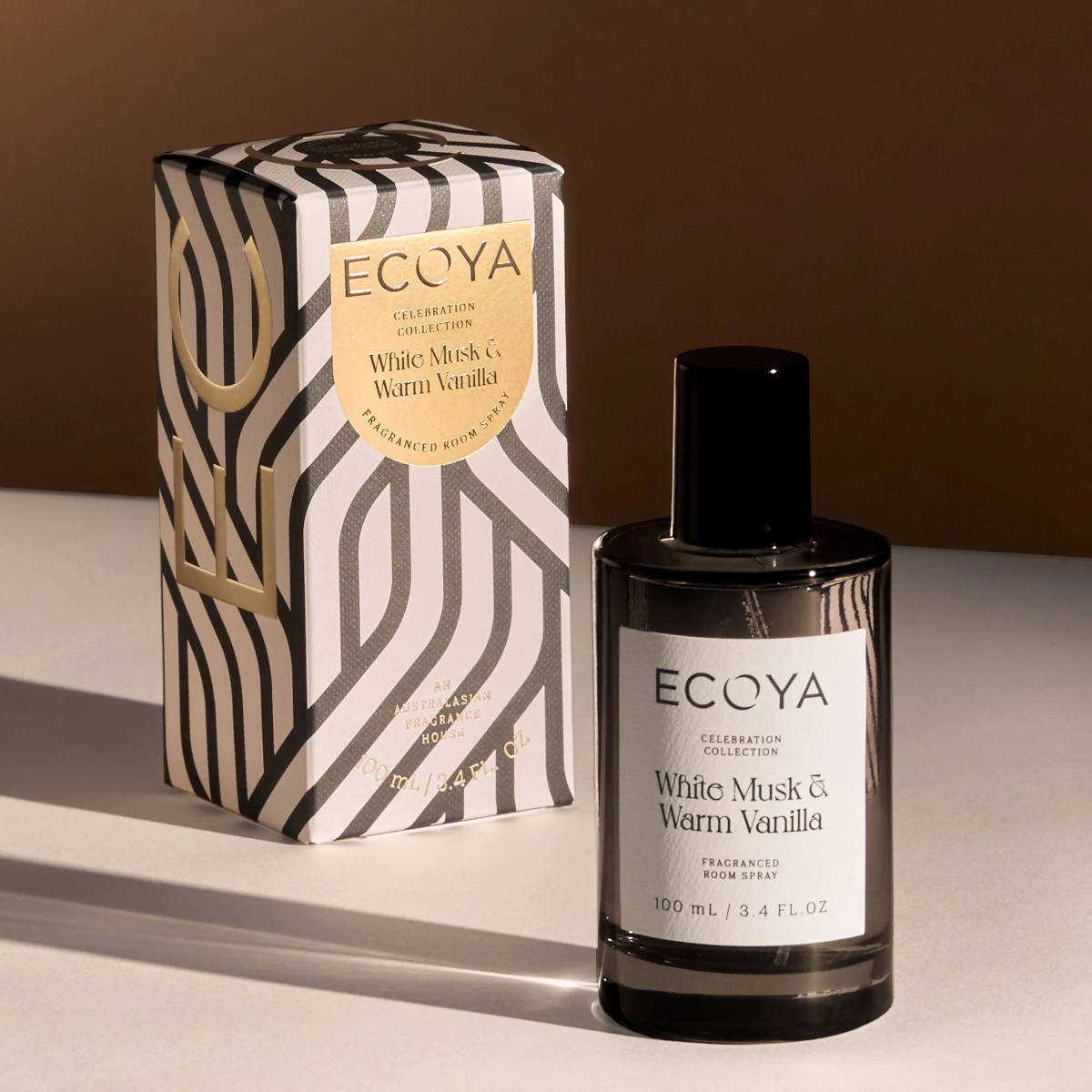 Ecoya Celebration Collection White Musk & Warm Vanilla Room Spray 100mL styled with its decorative gift box under warm lighting, showcasing the elegant festive packaging.