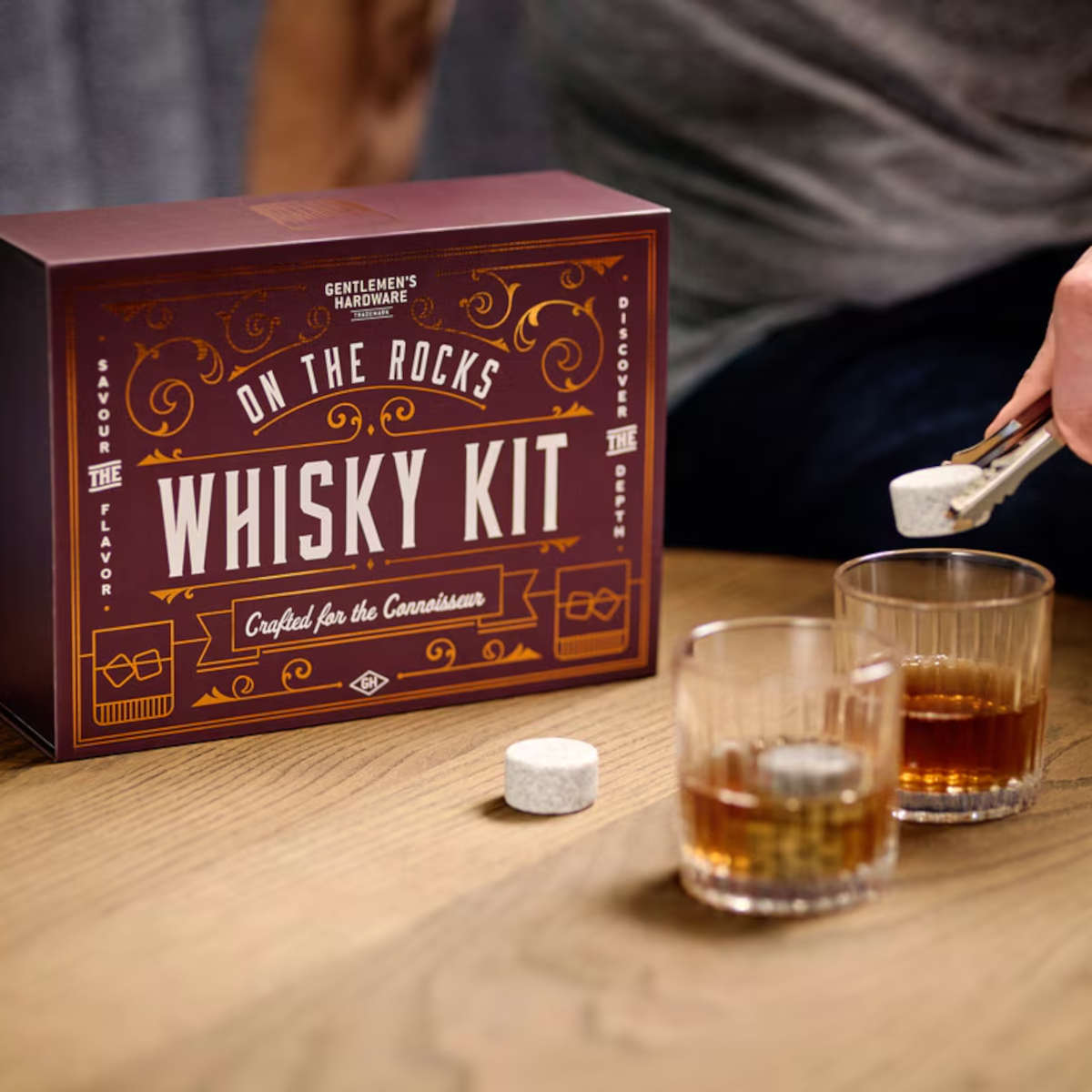 Lifestyle image of the Gentlemen's Hardware On The Rocks Whisky Kit in use, featuring whisky glasses, granite whisky stones, and tongs for an elevated whisky tasting experience.