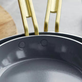 GreenPan Stanley Tucci Stainless Steel Frypan Set 20cm & 26cm with gold handles stacked together on white background