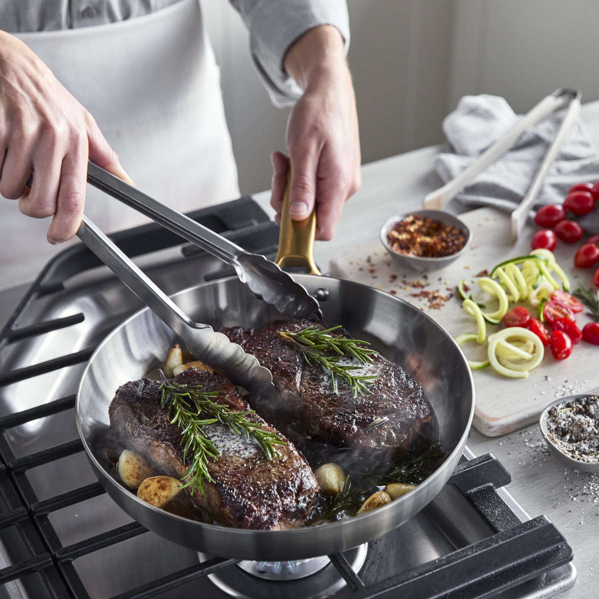 GreenPan Padova Stainless Steel Frypan 20cm – overhead view cooking steaks with rosemary