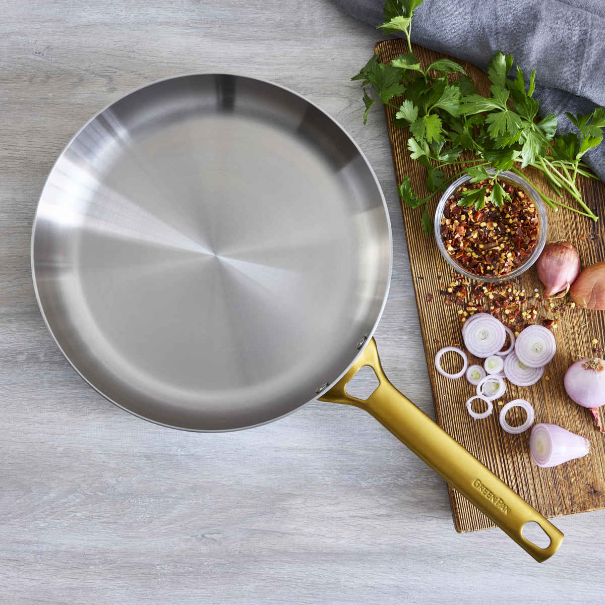 GreenPan Padova Stainless Steel Frypan 28cm – displayed on wooden board with mushrooms and herbs