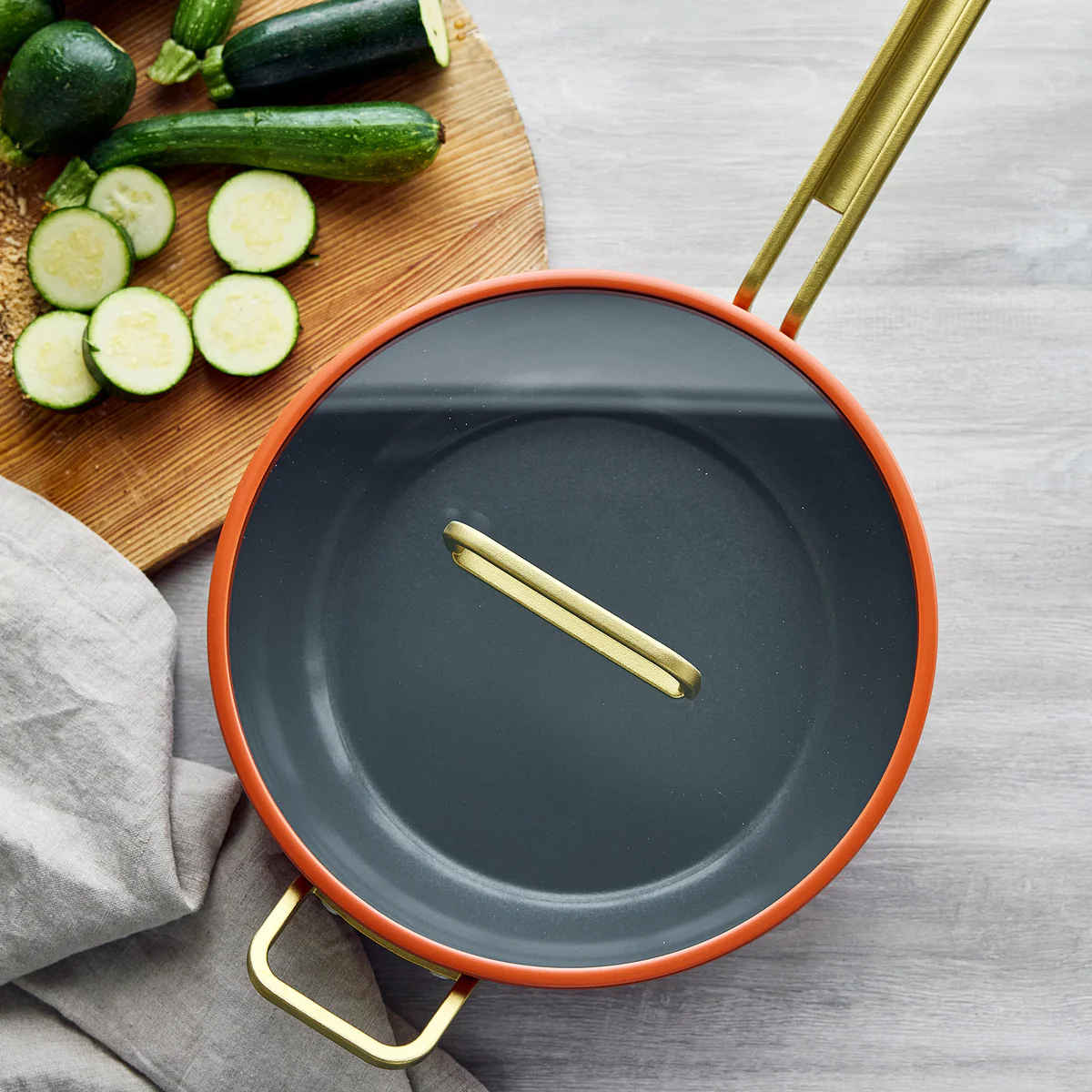 GreenPan Stanley Tucci Pan Junior Orange – top view with lid on beside fresh zucchini