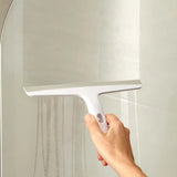 Squeegee in use clearing water from glass shower screen