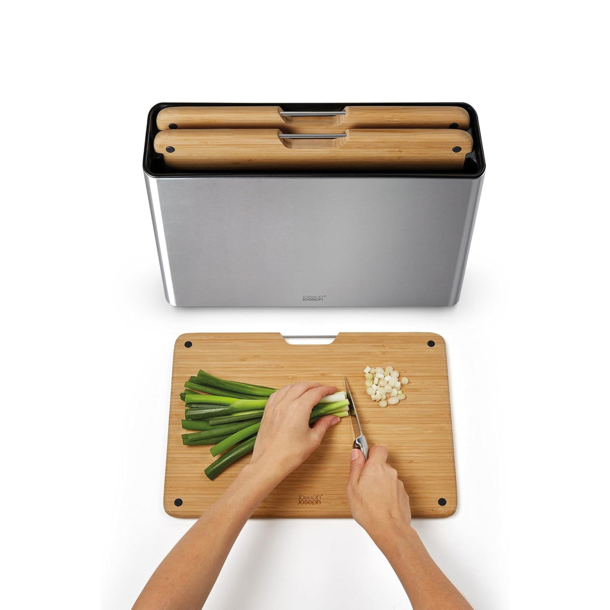 Person chopping green onions on Joseph Joseph bamboo board with steel storage set