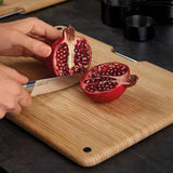 Joseph Joseph bamboo chopping board used to slice pomegranate on kitchen counter