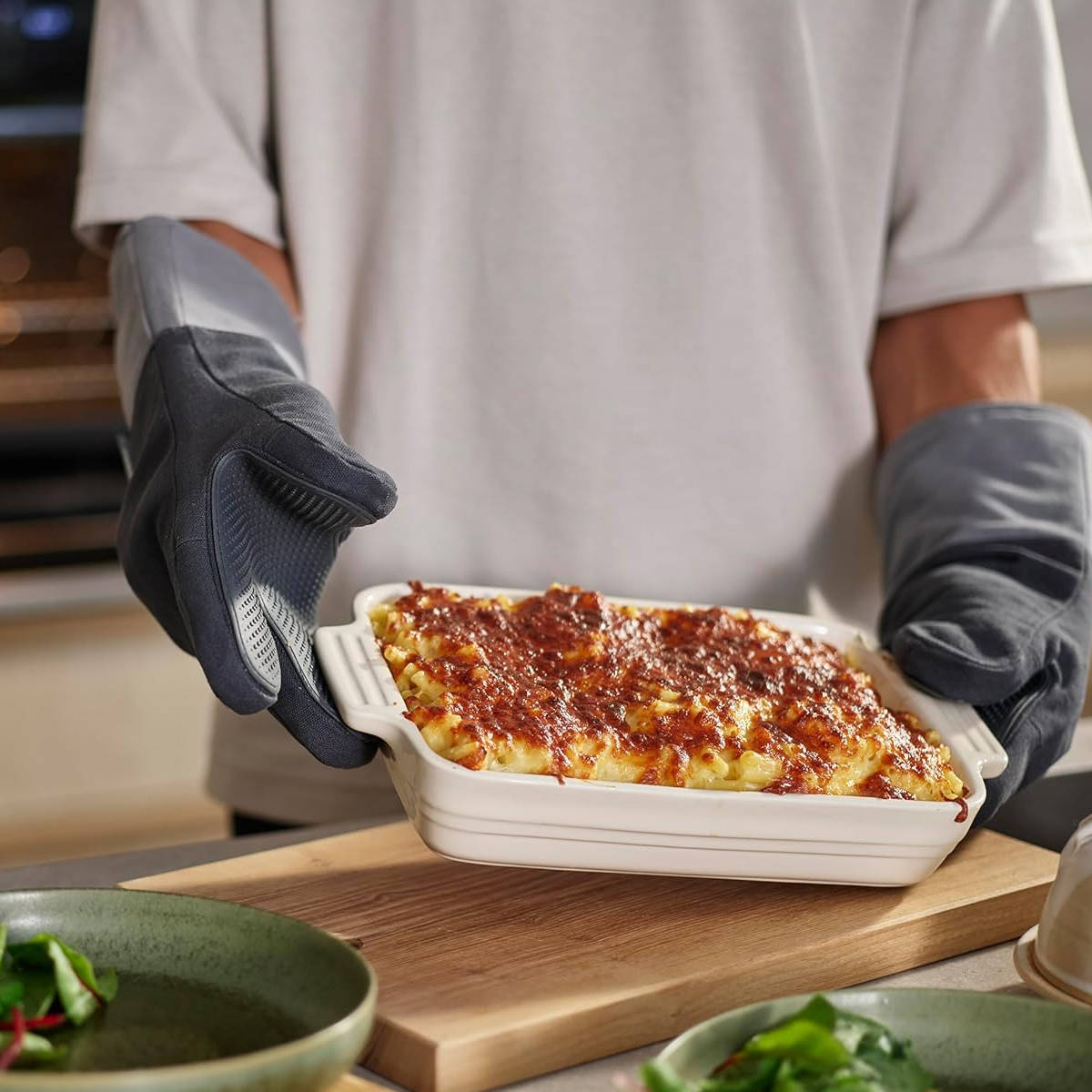 Person using Joseph Joseph Pinch oven gloves to hold hot baking dish