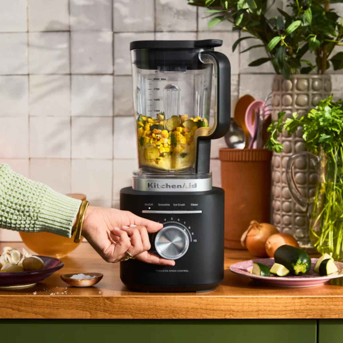 KitchenAid K200 Pure Power Blender Black Matte  – Lifestyle image of KitchenAid Pure Power Blender Black Matte in use, blending vegetables on a kitchen counter