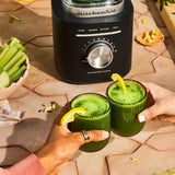KitchenAid Pure Power Blender in Matte Black with fresh green smoothies served in glasses on an outdoor table.