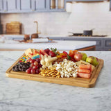 Farberware SnackleBox with Bamboo Board 30 x 40cm - Wooden charcuterie board with fruits, nuts, and cheeses on a kitchen counter.