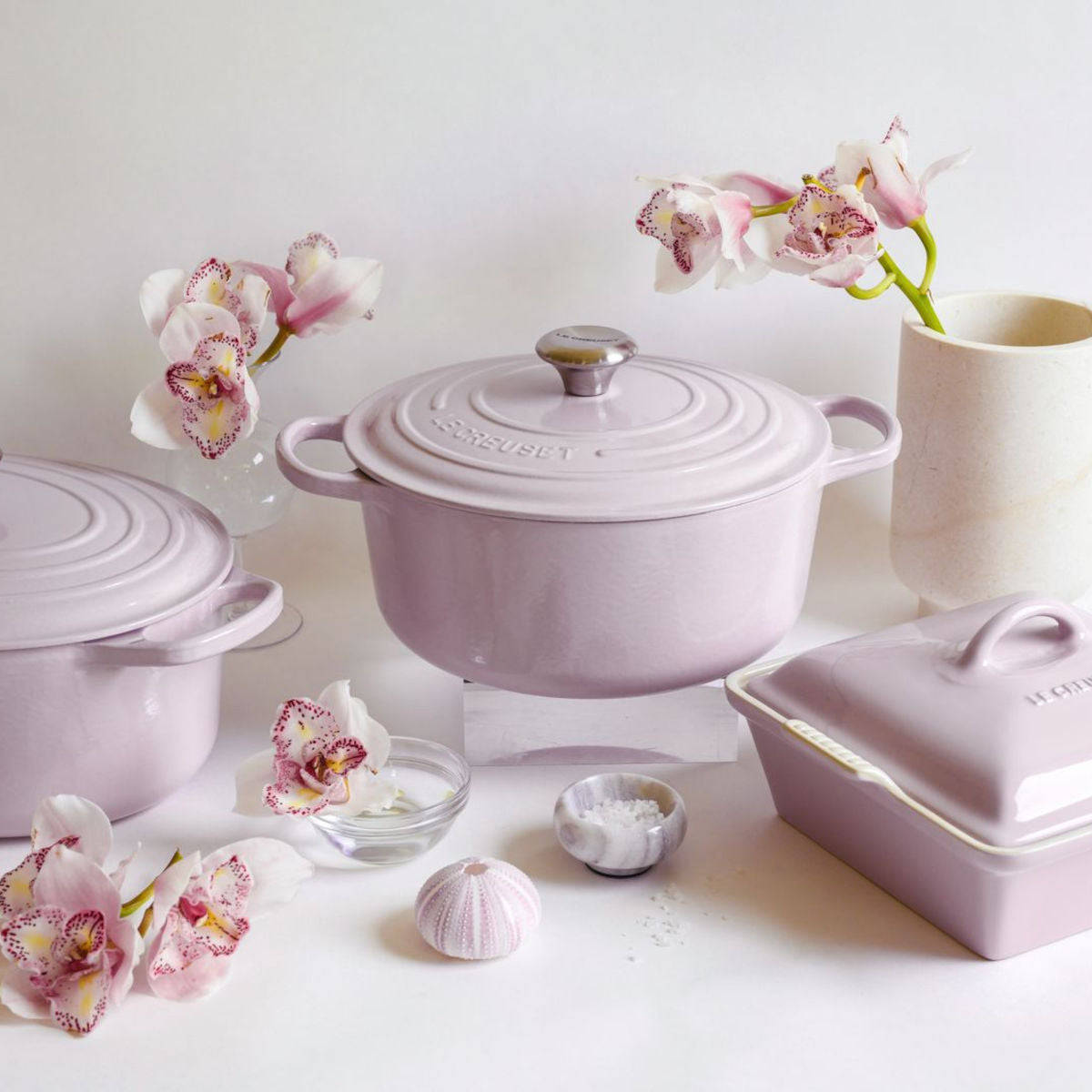 Le Creuset Shallot casserole with matching bakeware styled with orchids and neutral decor.