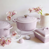 Le Creuset Shallot casserole with matching bakeware styled with orchids and neutral decor.