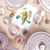 Close-up of Le Creuset Shallot round casserole styled with orchids and pink tones.