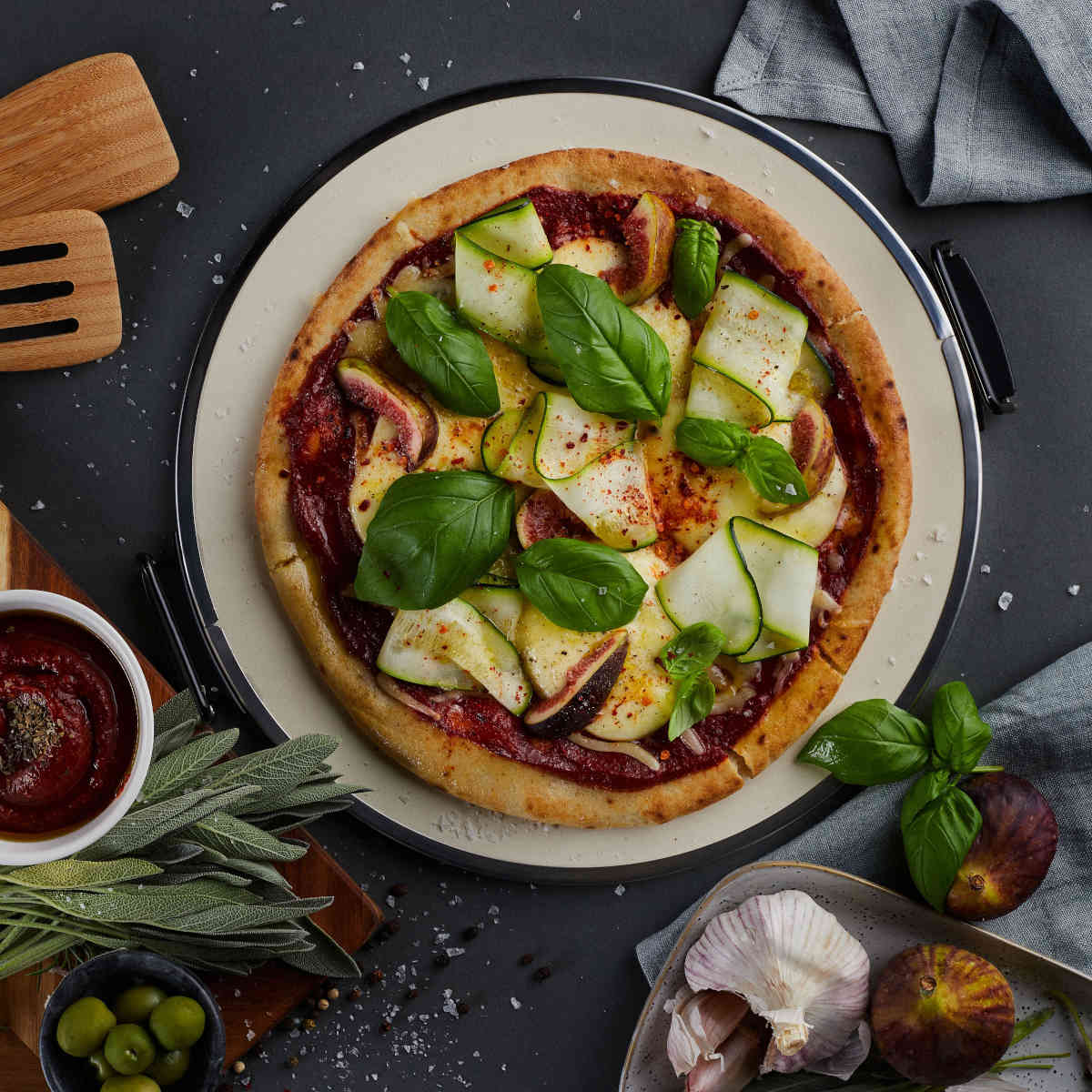 Top view of pizza baked in MasterPro Ultimate Pizza Oven with fresh basil and zucchini toppings