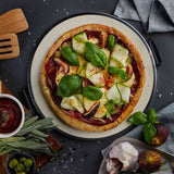 Top view of pizza baked in MasterPro Ultimate Pizza Oven with fresh basil and zucchini toppings