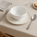 Pillivuyt Standard Bowl 13.5cm - White bowl and plate set on a beige tablecloth with silverware.