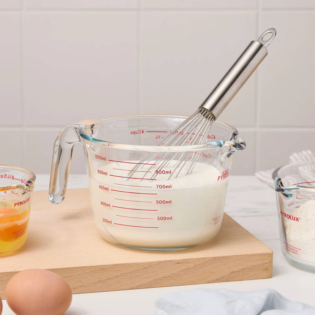 Pyrolux Measuring Jug 2 Cup (500ml) – whisk in jug with milk, eggs and other ingredients nearby